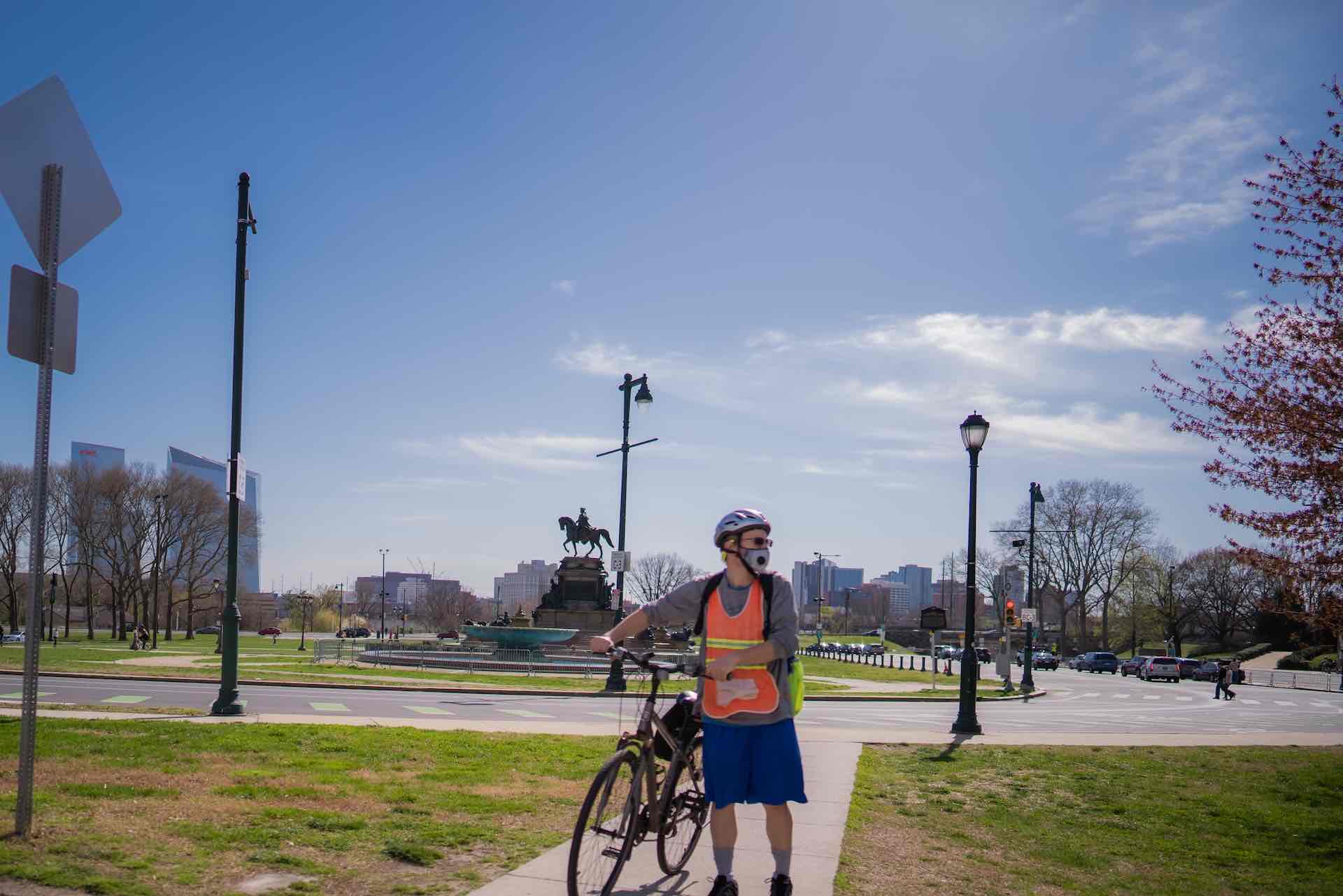 man standing next to his bike wearing shorts, hoodie and a face mask