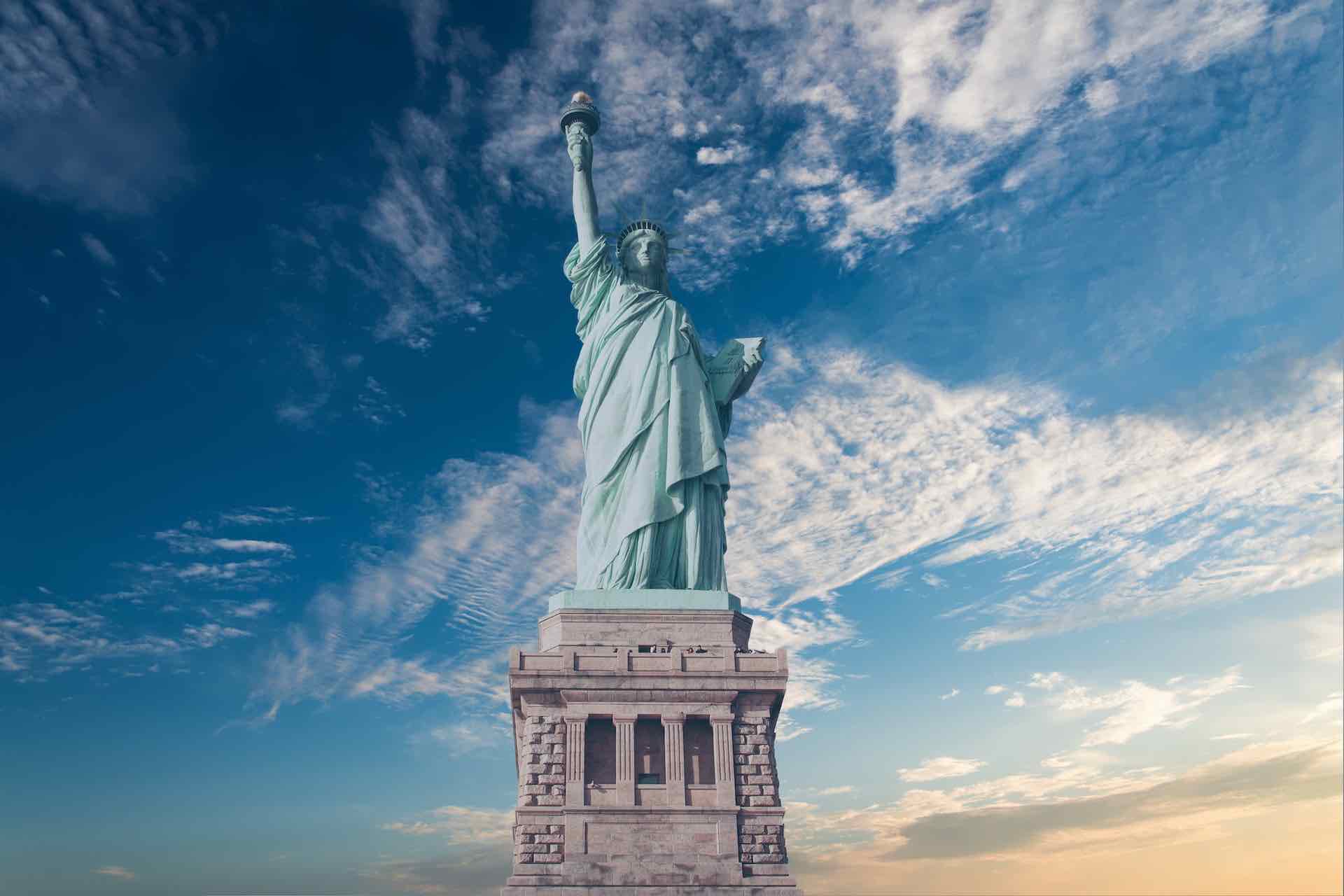 image of the Statue of Liberty and in the background a few whips clouds and beautiful blue sky