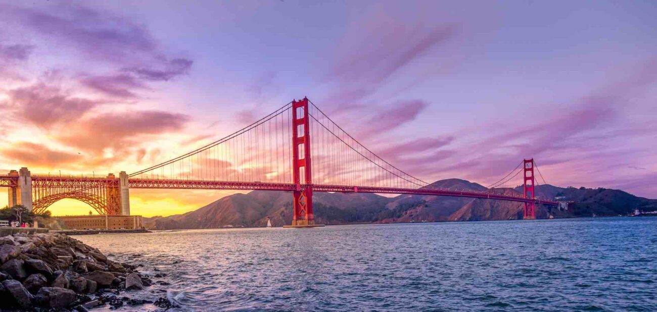 sun rising behind the Golden Gate Bridge, you need to cross this bridge if you want to drive from the airport to Napa Valley